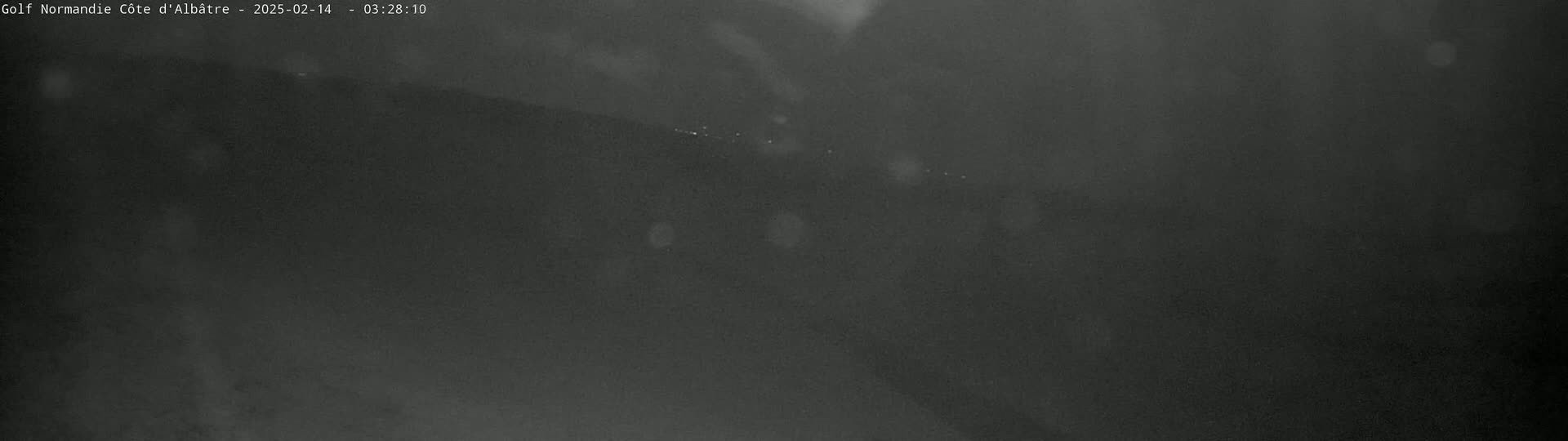 A dark, blurry image shows a landscape at night with light snowfall or rain.