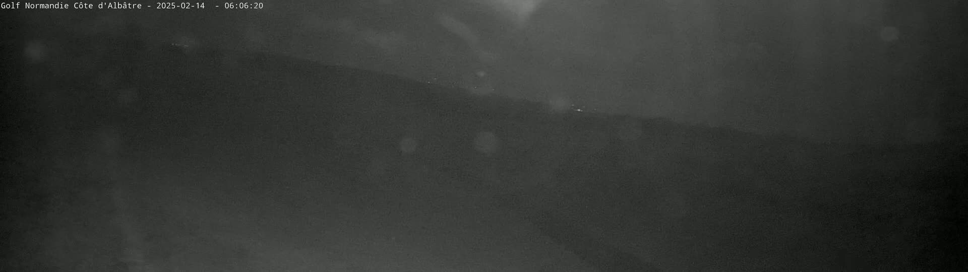 A dark, blurry image shows a hill or mountain range at night in foggy or hazy conditions.