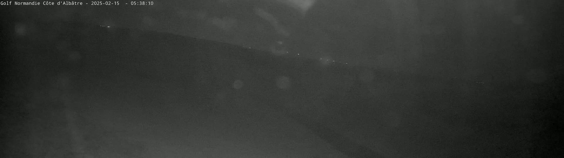 A dark, blurry image shows a landscape at night under a cloudy sky, with a few faint lights visible in the distance.