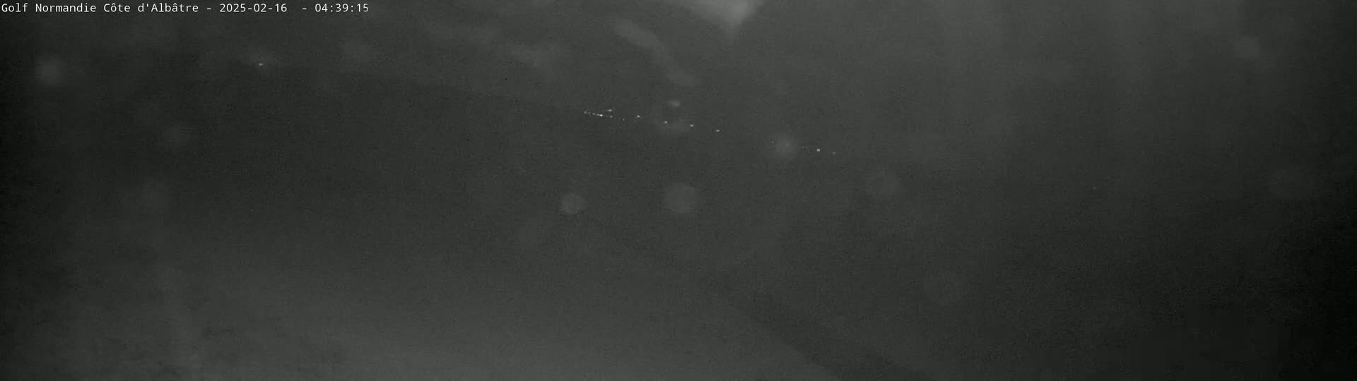 A dark, blurry image shows a few distant lights in the night, possibly under a slightly snowy or hazy sky.