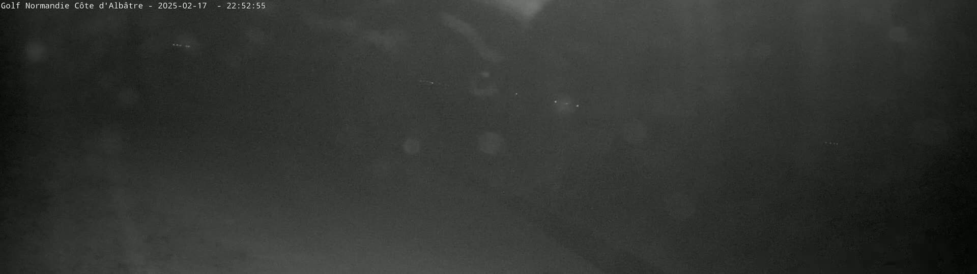 A dark, blurry nighttime image shows a few faint lights in the distance.