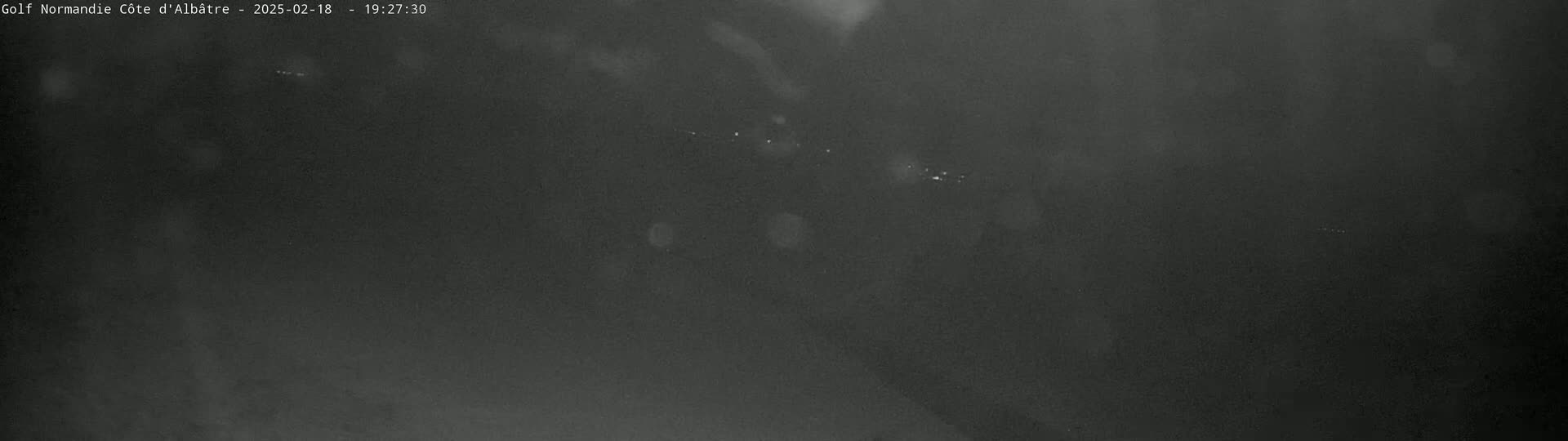 A dark, blurry nighttime image shows a few faint lights in the distance.