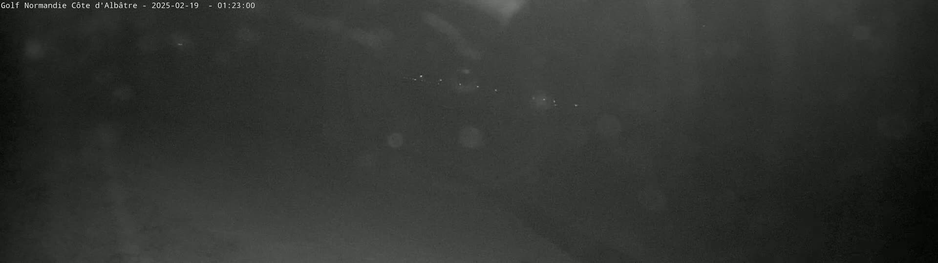 A dark, blurry nighttime image shows a few faint lights in the distance.