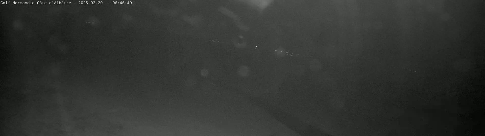 A dark, blurry nighttime image shows a few faint lights in the distance.