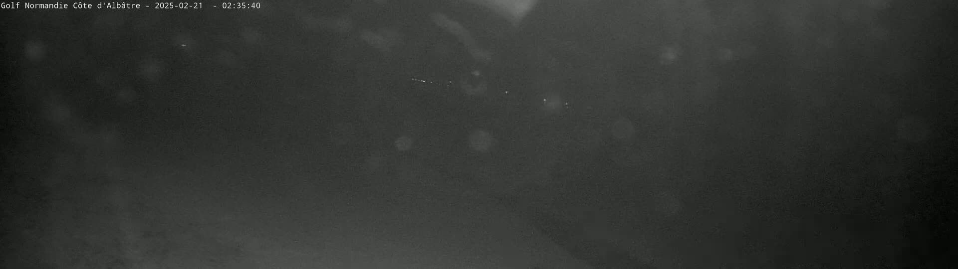 A blurry, dark nighttime image shows a few faint lights in the distance.