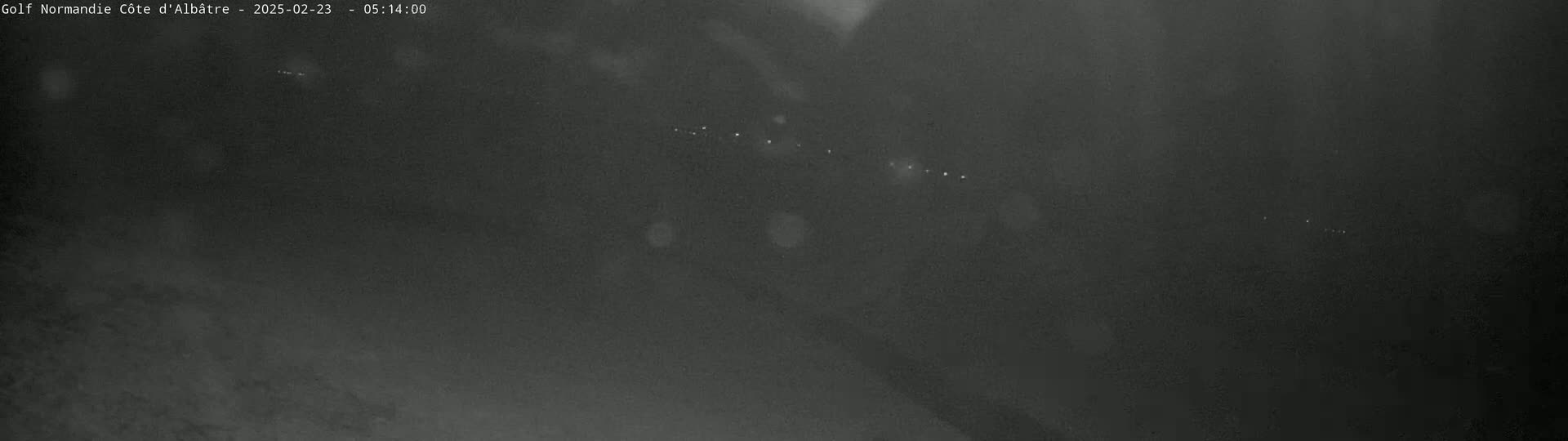 A blurry, nighttime image shows a dimly lit roadway with faint lights visible in the distance.