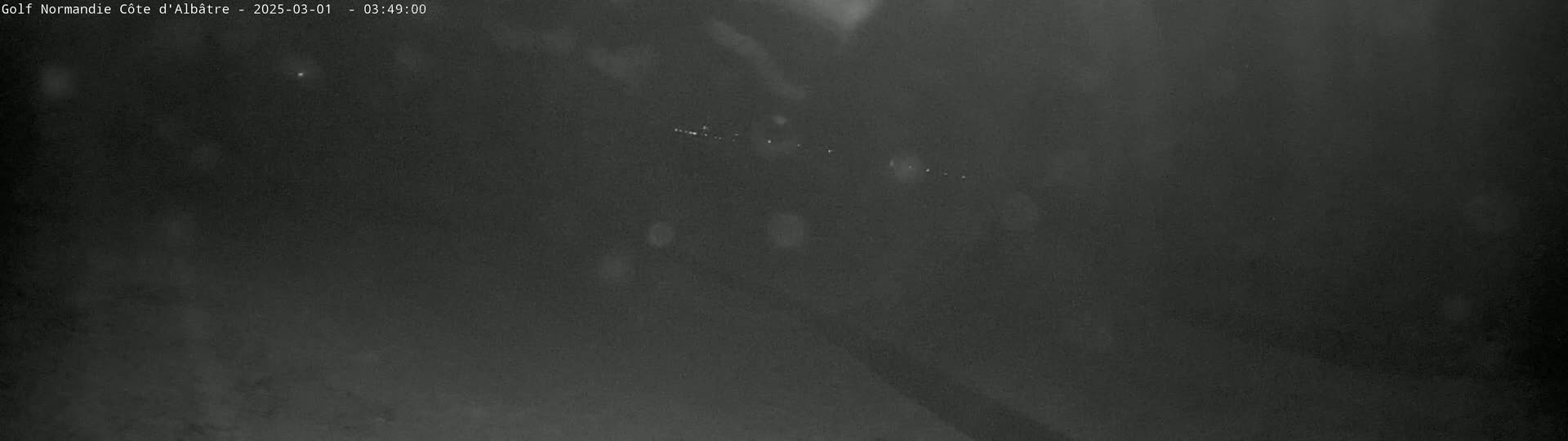 A dark, blurry nighttime image shows a few faint lights in the distance.