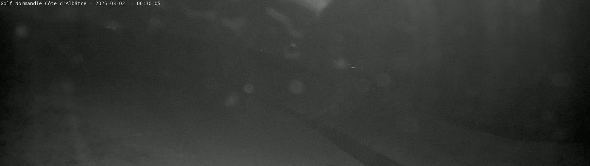 A dark, blurry image shows a nighttime outdoor scene with light precipitation.