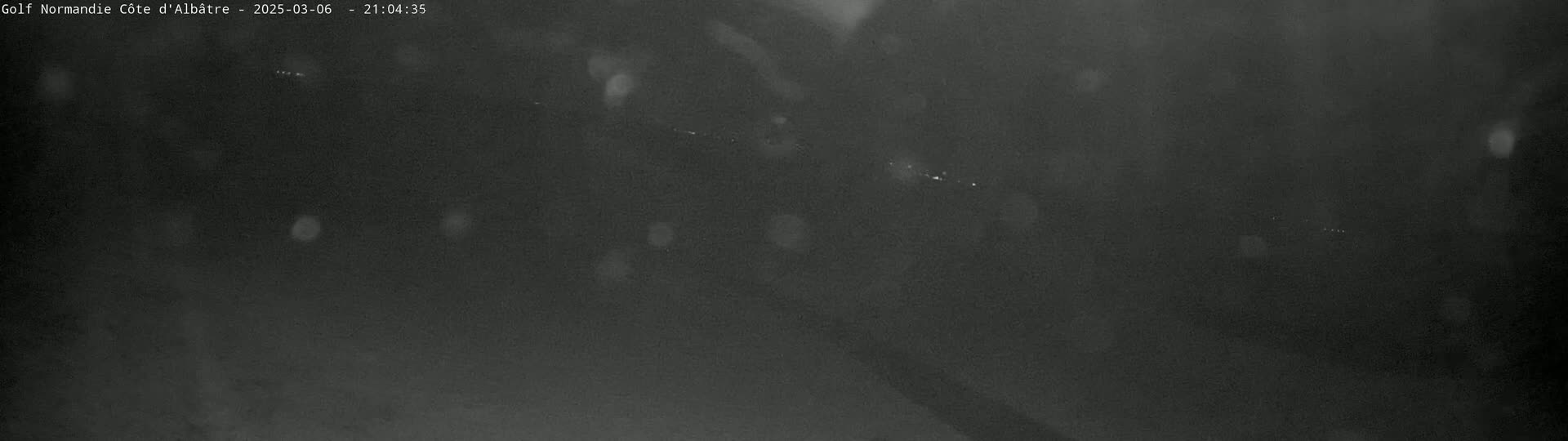 A dark, blurry nighttime scene with light rain or snow falling.