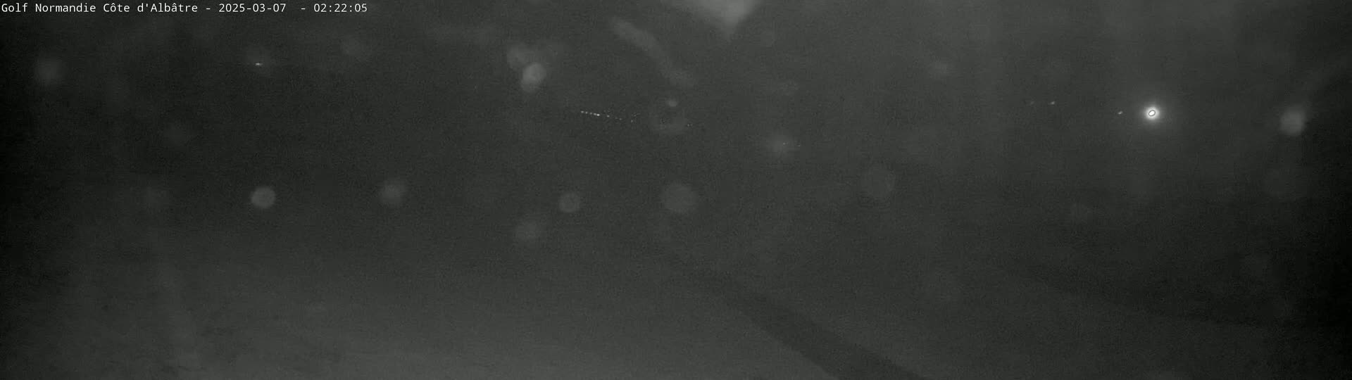 A dark, blurry nighttime scene with light rain or snow falling.