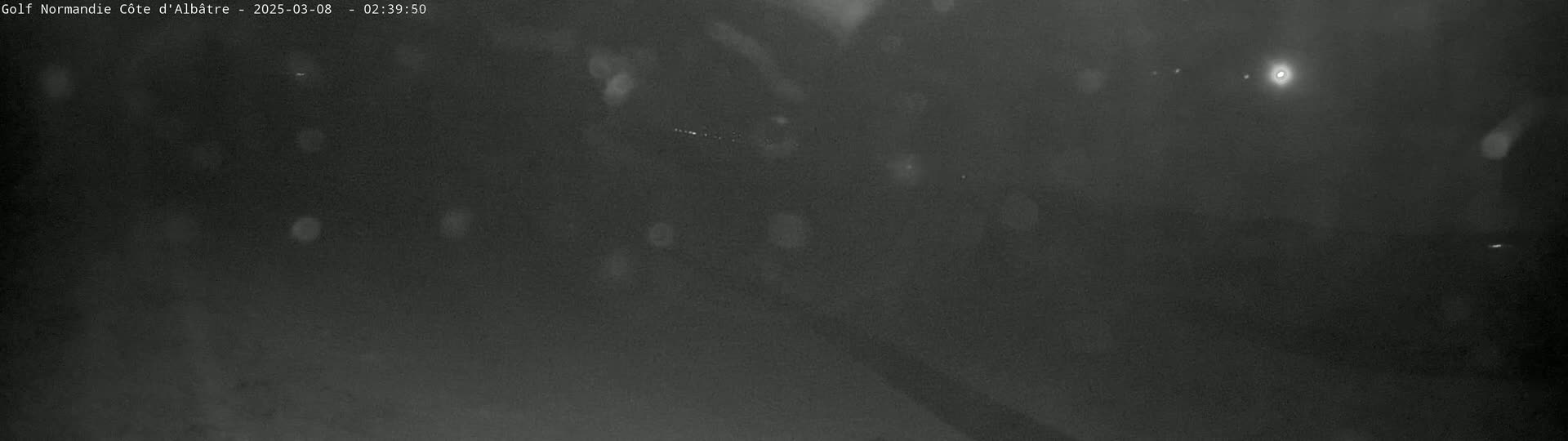 A dark, blurry nighttime scene with rain or snow falling.