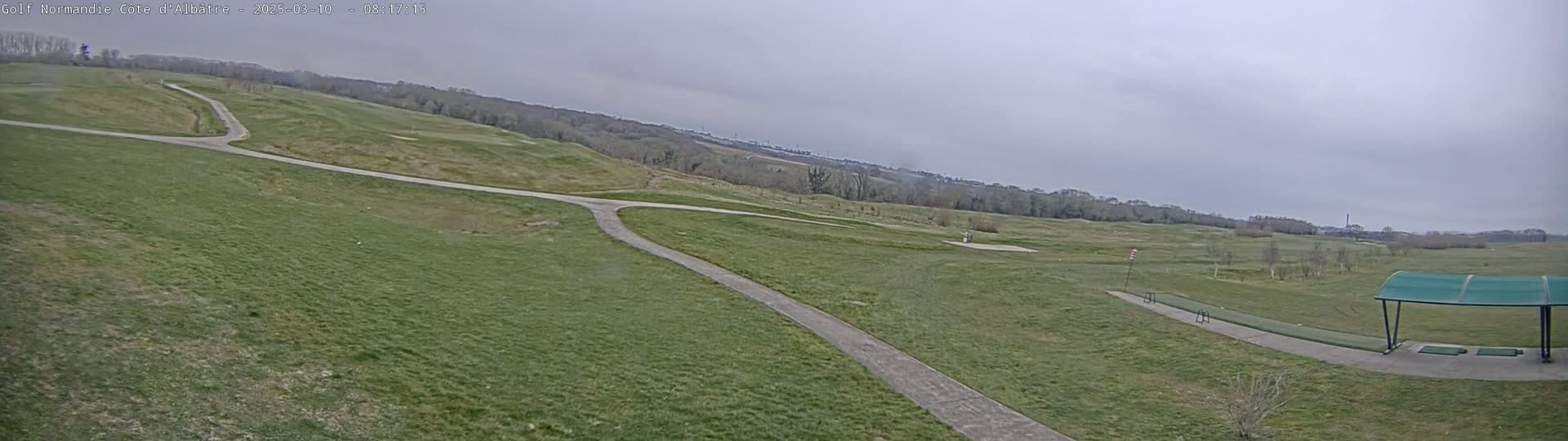 A paved path winds through a grassy golf course under an overcast sky.