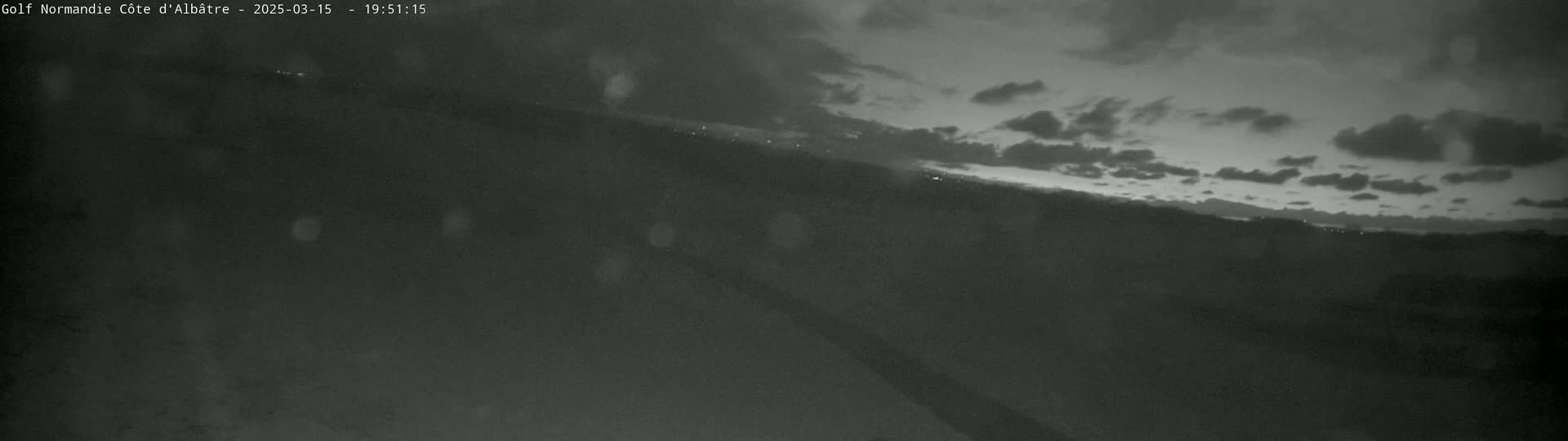 A nighttime, low-light view of a landscape under a partly cloudy sky.