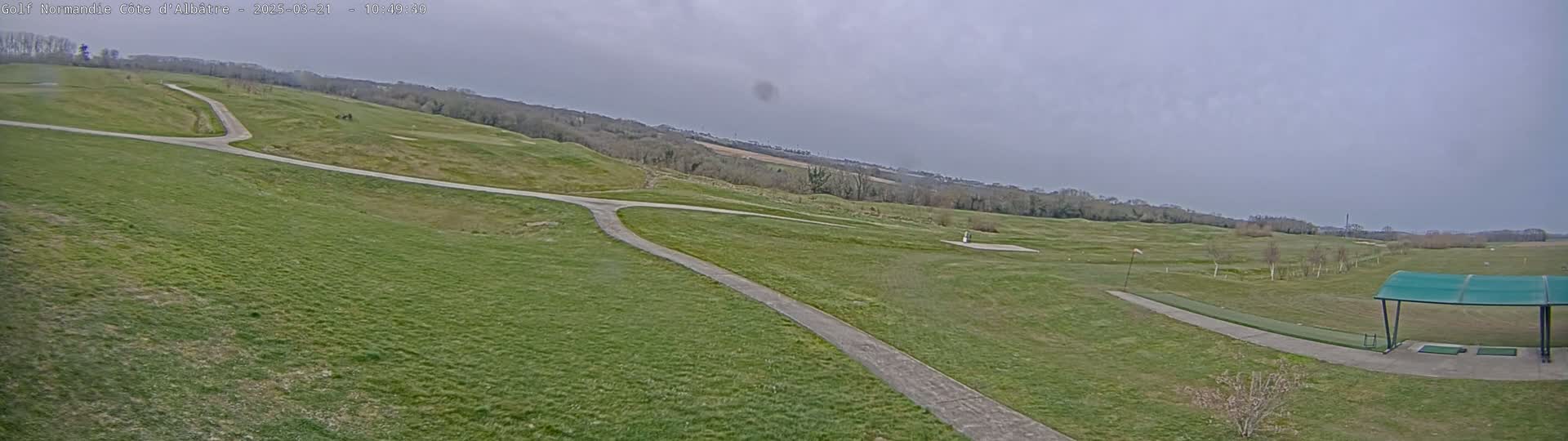 A paved path winds through a grassy golf course under an overcast sky.