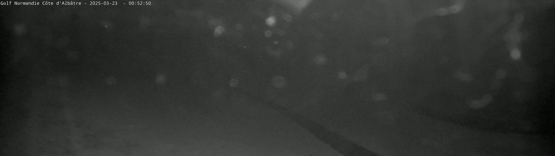 A dark, nighttime scene shows a blurry, indistinct landscape with faint, scattered lights.
