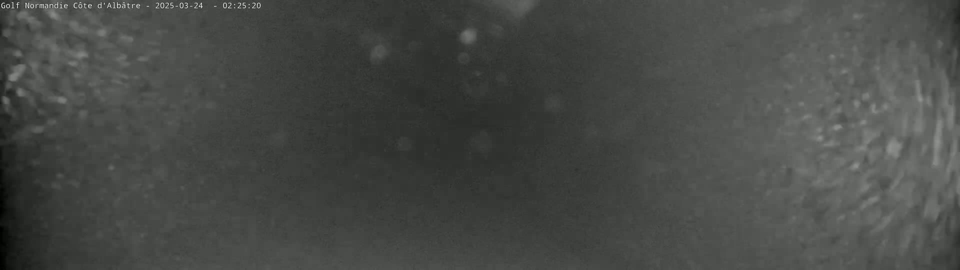 A blurry, dark gray image shows a nighttime scene with light snow or rain falling.