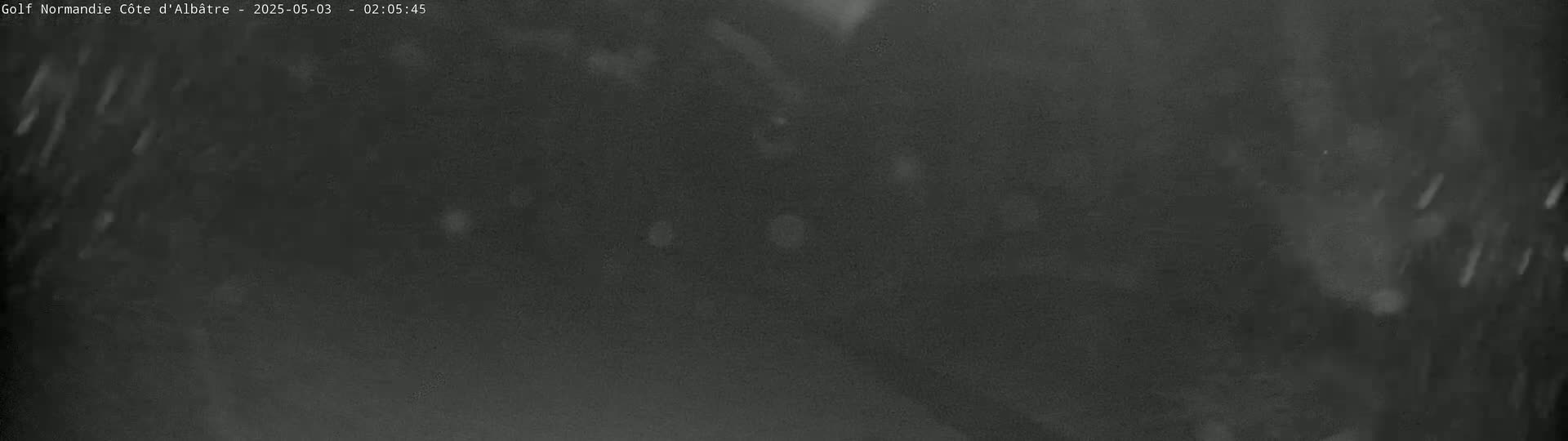 A dark, blurry image shows light streaks falling from the top, suggesting it is snowing or raining at night.