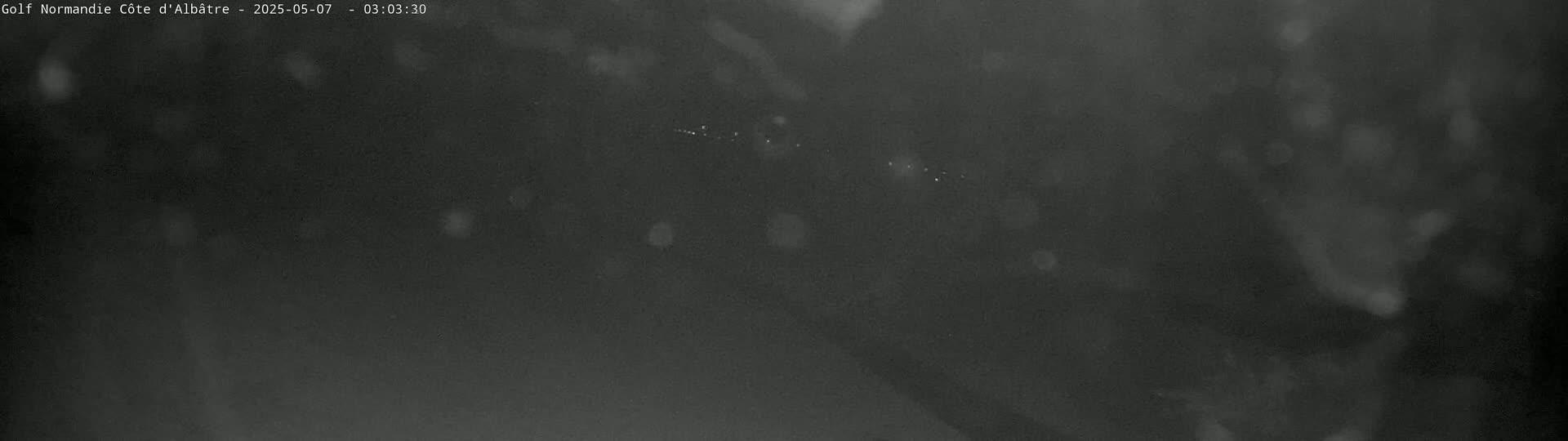A dark, blurry nighttime image shows a line of faint lights in the distance.