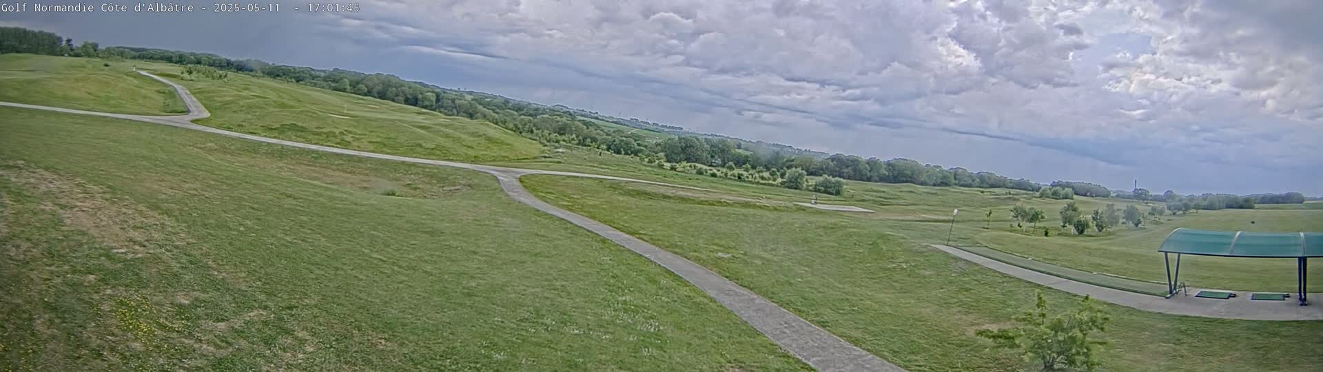 A golf course with winding paths under a partly cloudy sky.