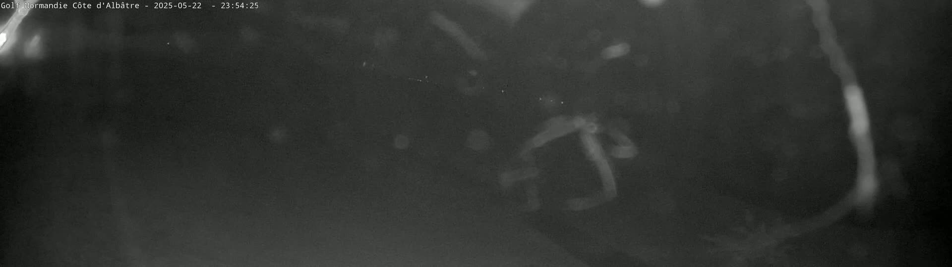 A blurry, low-light image shows a dark, possibly nighttime scene with indistinct shapes and faint, glowing areas.