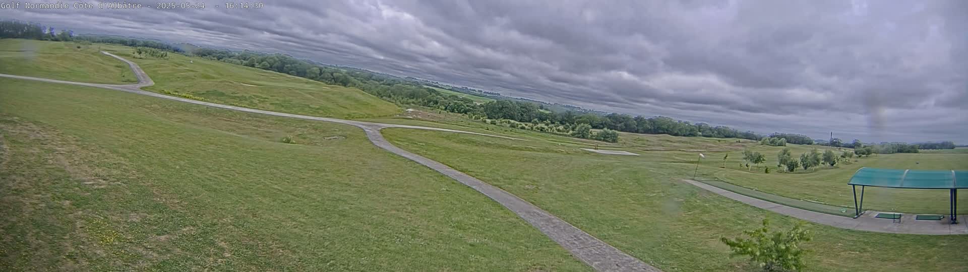 A golf course with paved pathways under a cloudy sky.