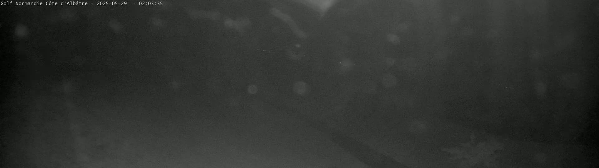 A dark, blurry image shows a night scene with faint, scattered light sources.
