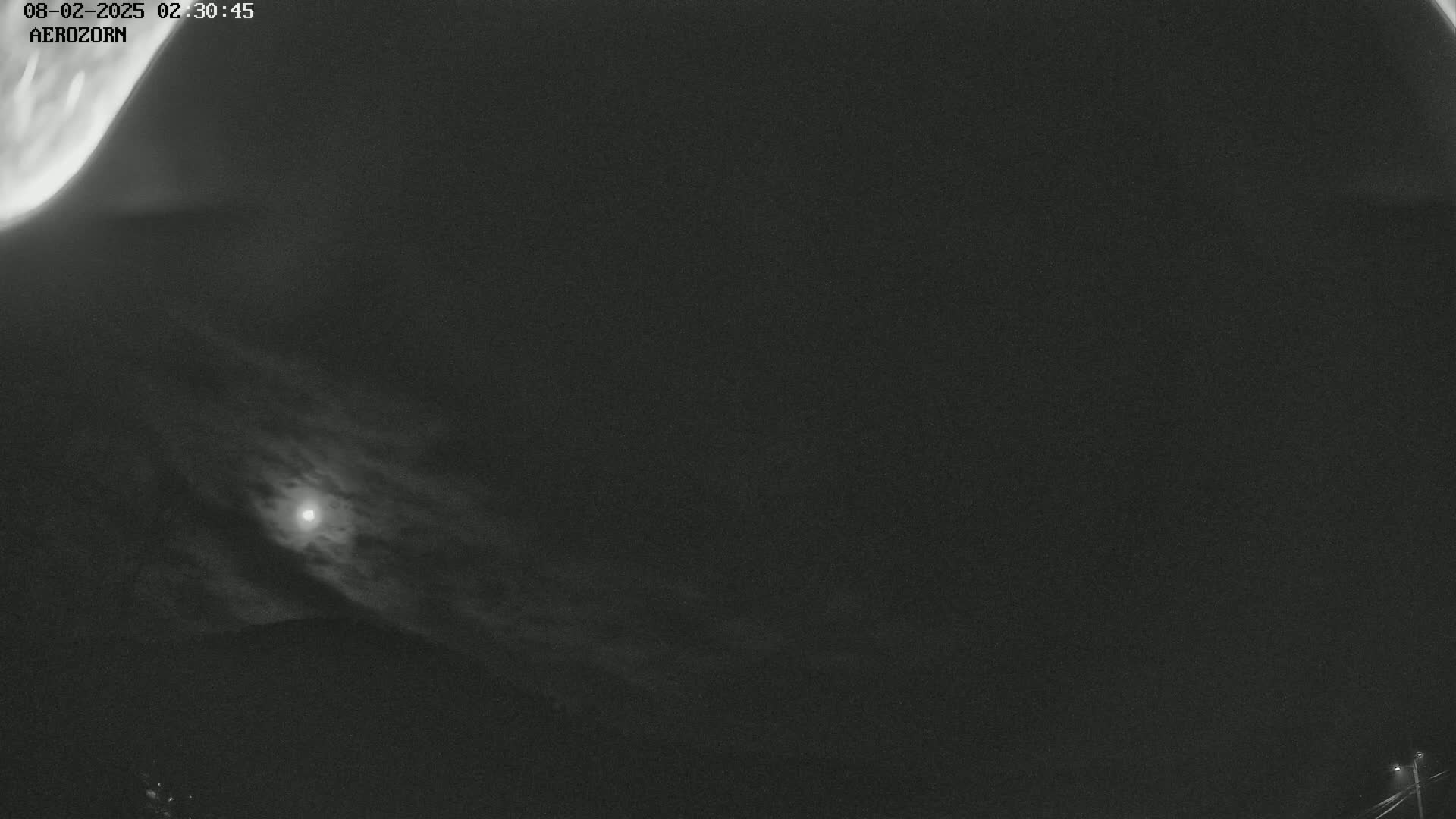 A nighttime, cloudy scene shows a bright moon partially obscured by clouds, with a faint aurora borealis visible in the upper left corner.