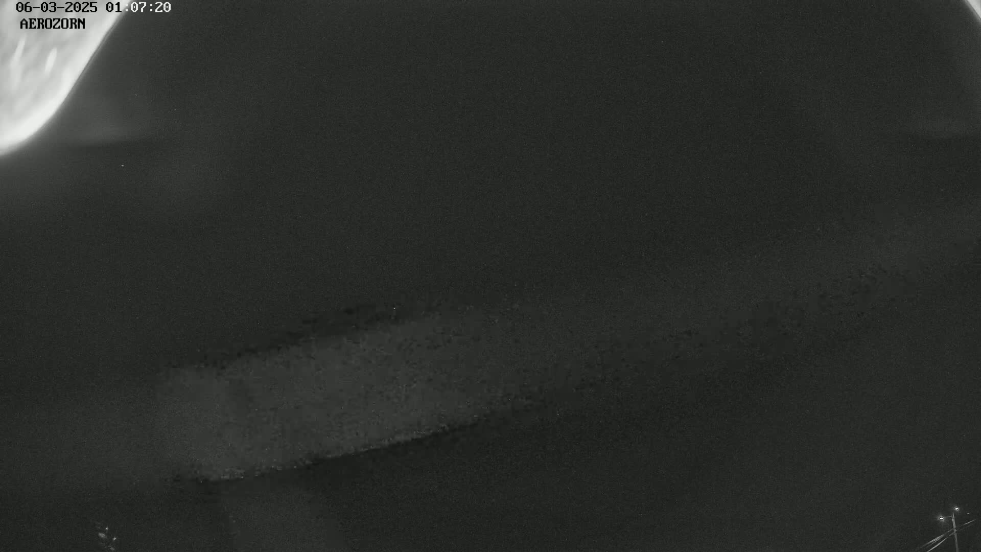 A low-light, nighttime image shows a long, horizontal streak of light across a dark sky.