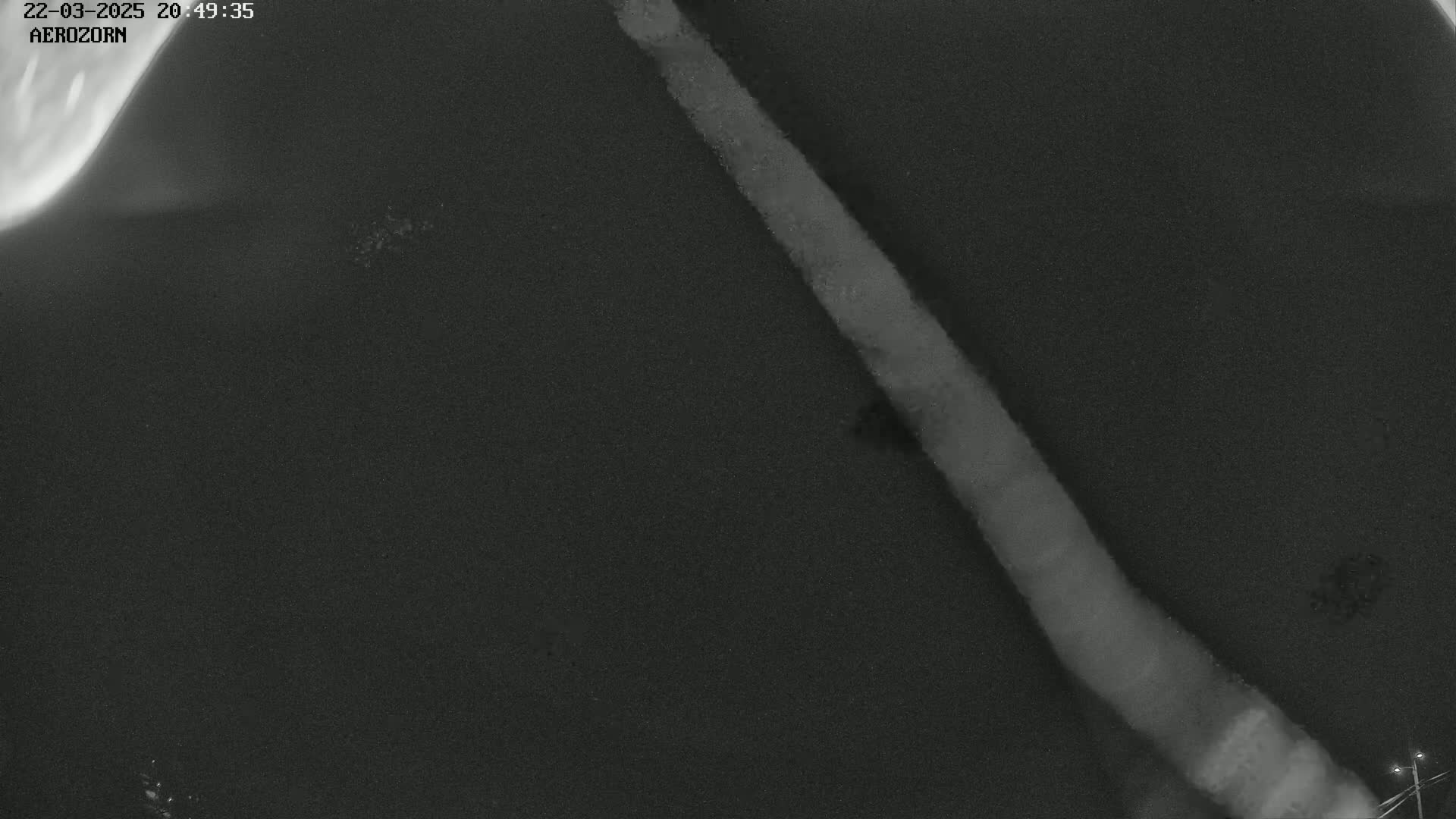A long, light-colored streak diagonally crosses a dark, grainy surface under a night sky.