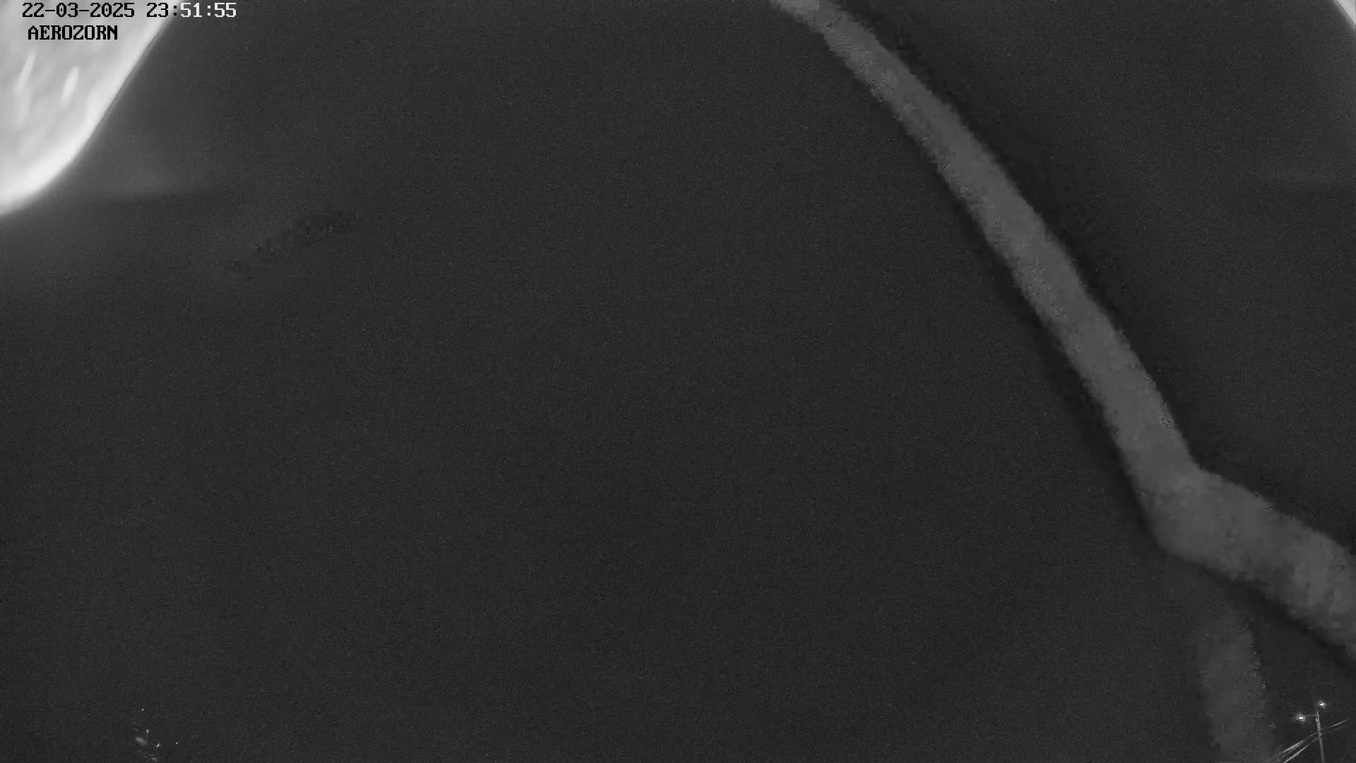 A dark, nighttime image shows a bright, vertical streak of light against a dark, textured background.