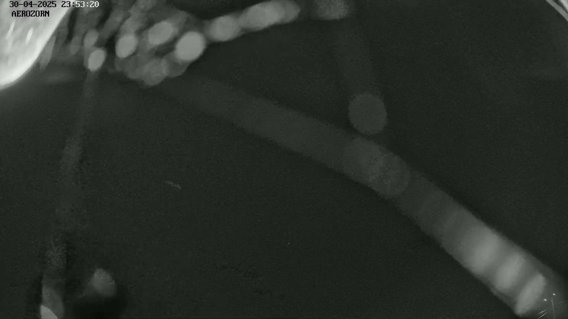 A grainy, dark image shows a blurry, diagonal light source against a mostly black background with a few brighter spots.