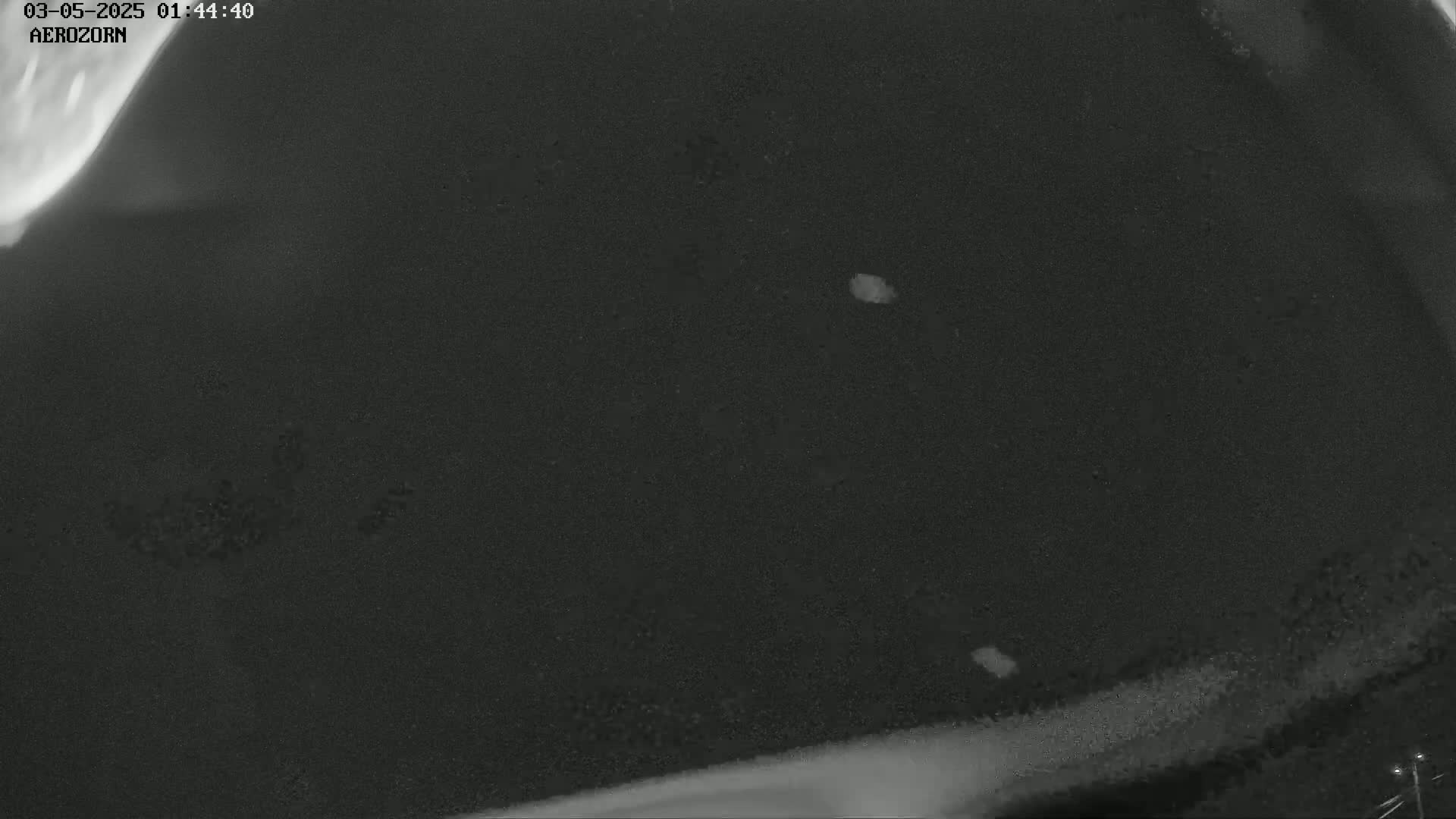 A dark, grainy nighttime image shows a few small, bright spots against a mostly black background.