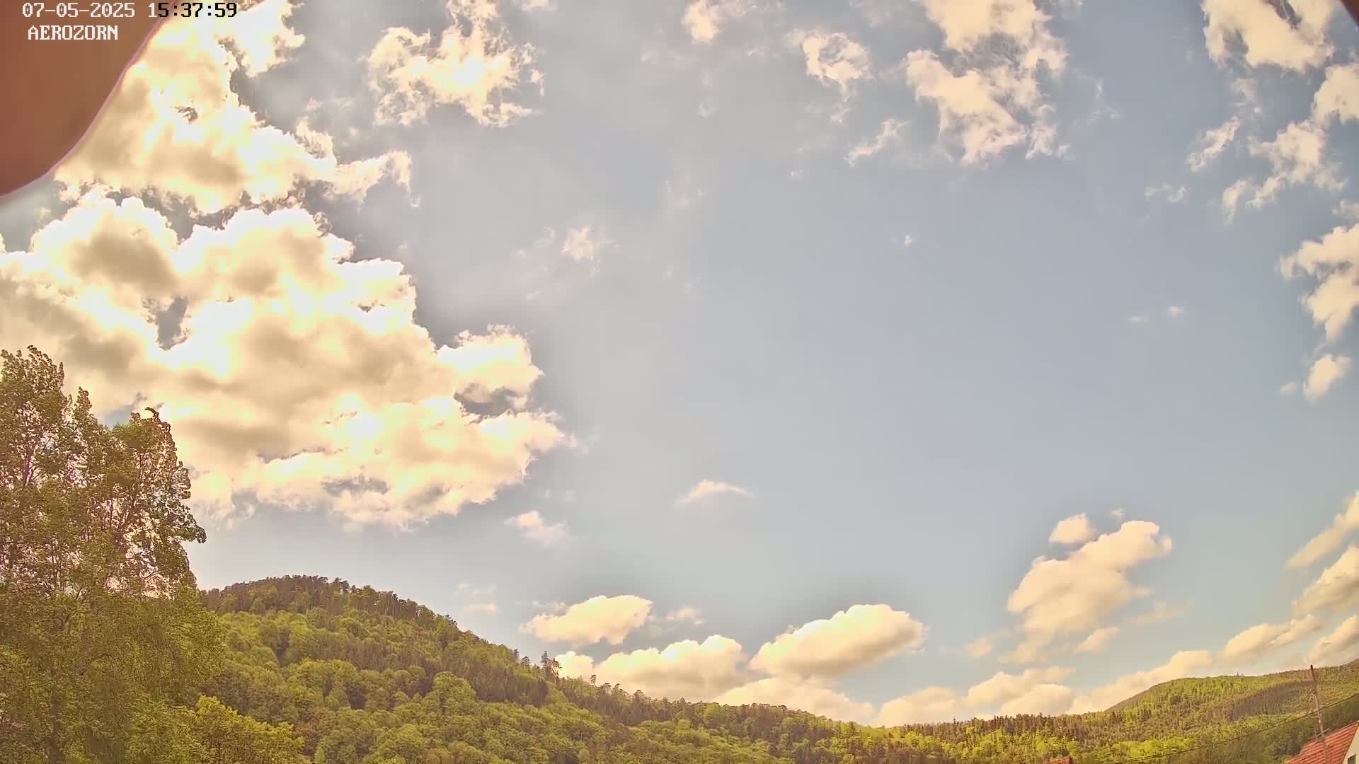 A partly cloudy sky is visible above a lush green hill under a mostly clear sky.