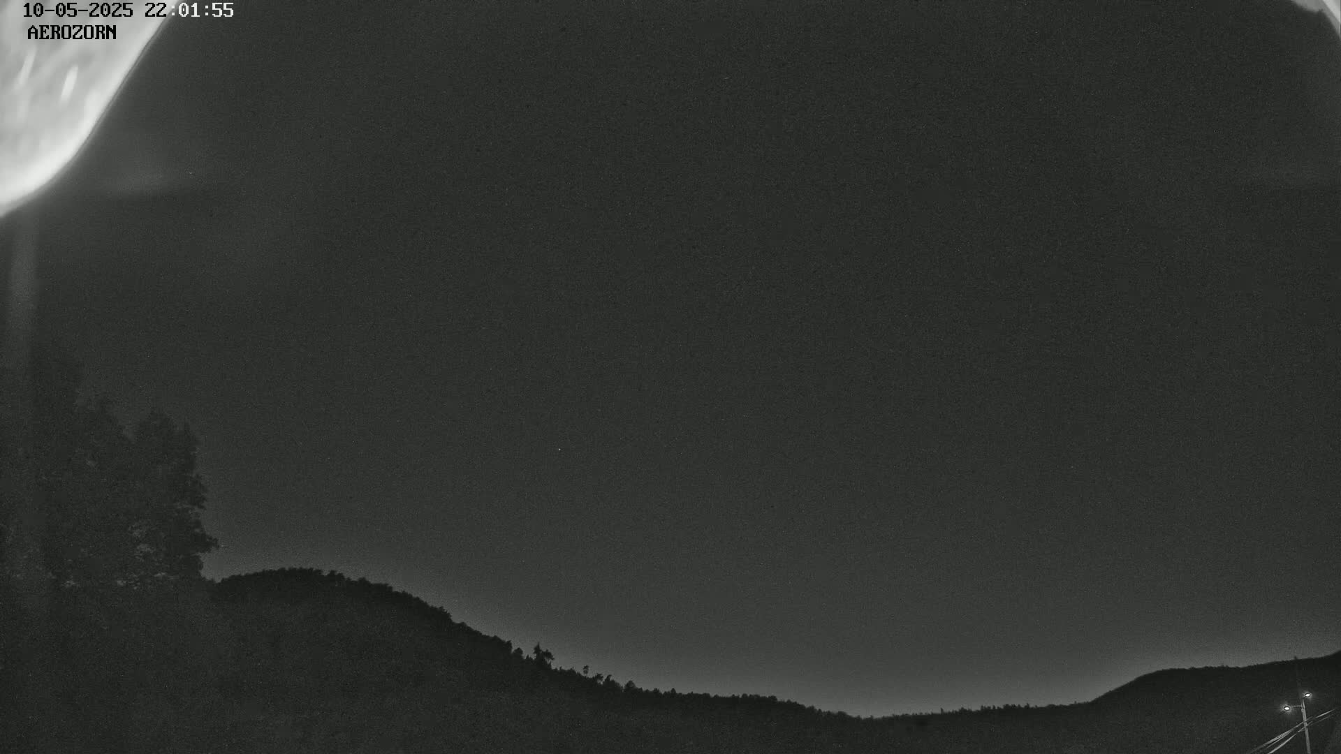 A nighttime view shows a dark sky with faint aurora borealis over a silhouetted hilly landscape.
