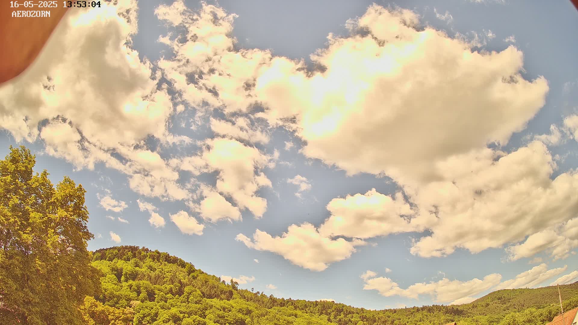 A partly cloudy sky is visible above a lush green hillside.