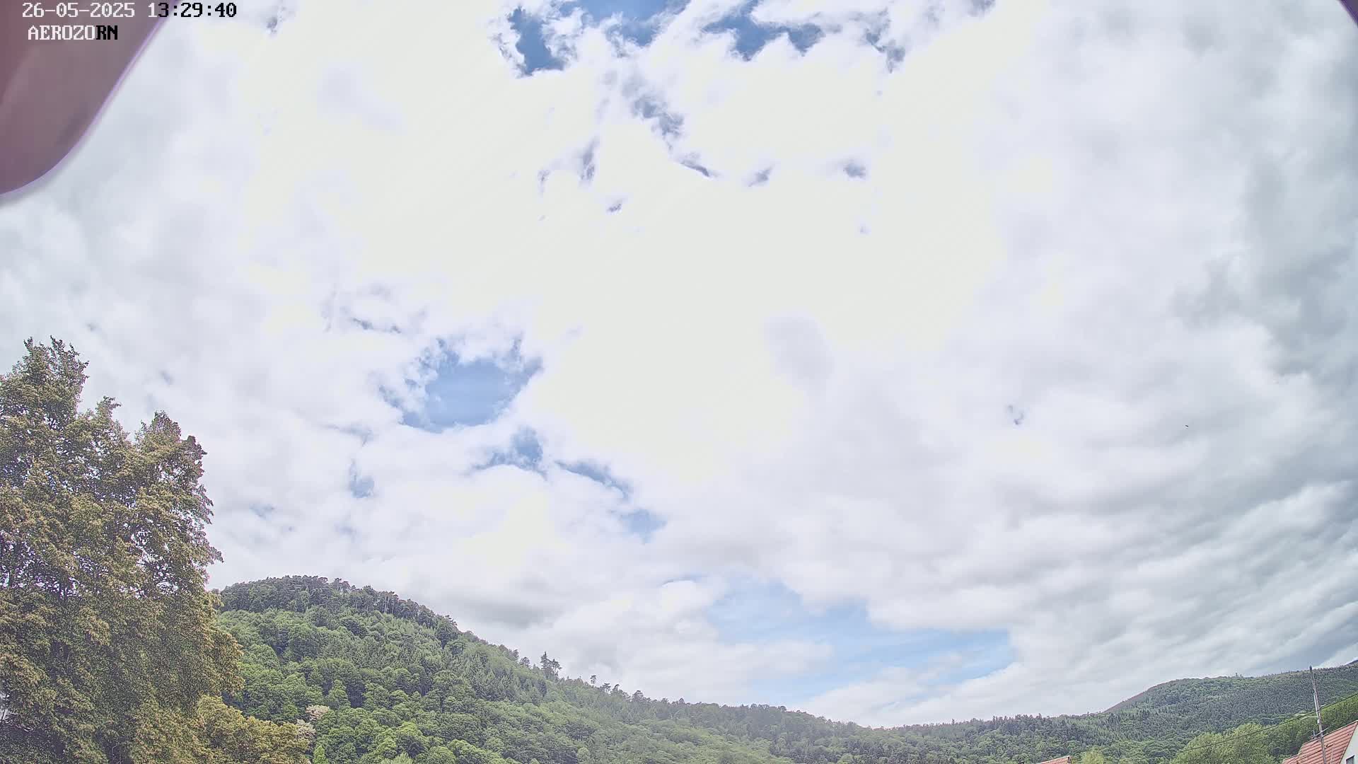 A partly cloudy sky overlooks a lush green hillside.