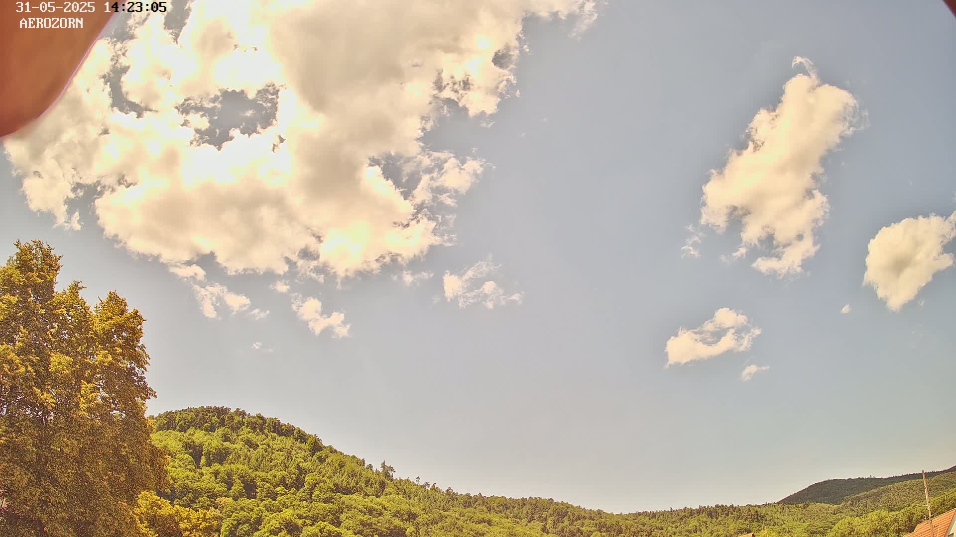 A partly cloudy sky is visible above a lush green hillside.