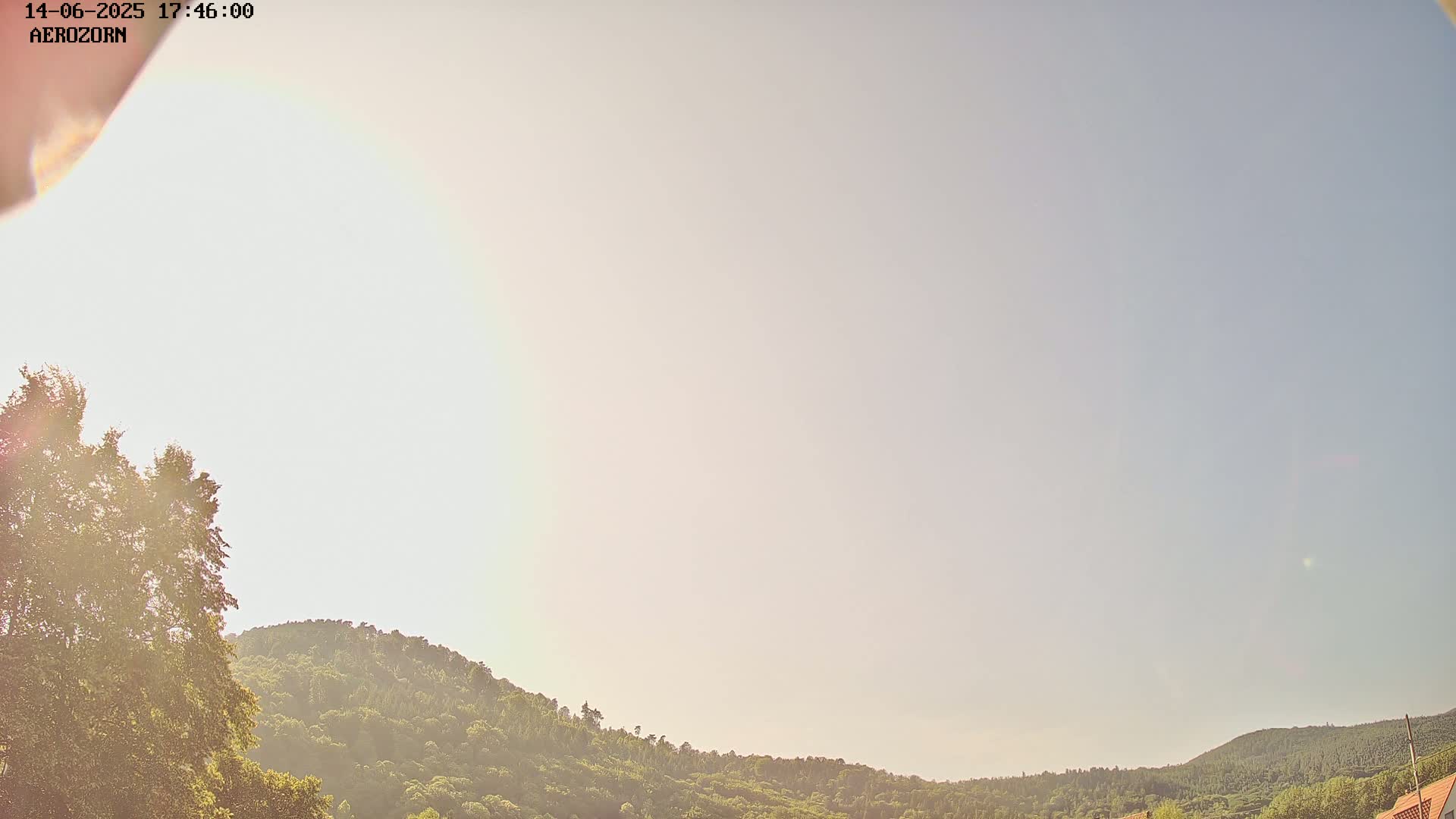 A mostly clear sky brightens the lush green hillsides under a nearly cloudless sky.