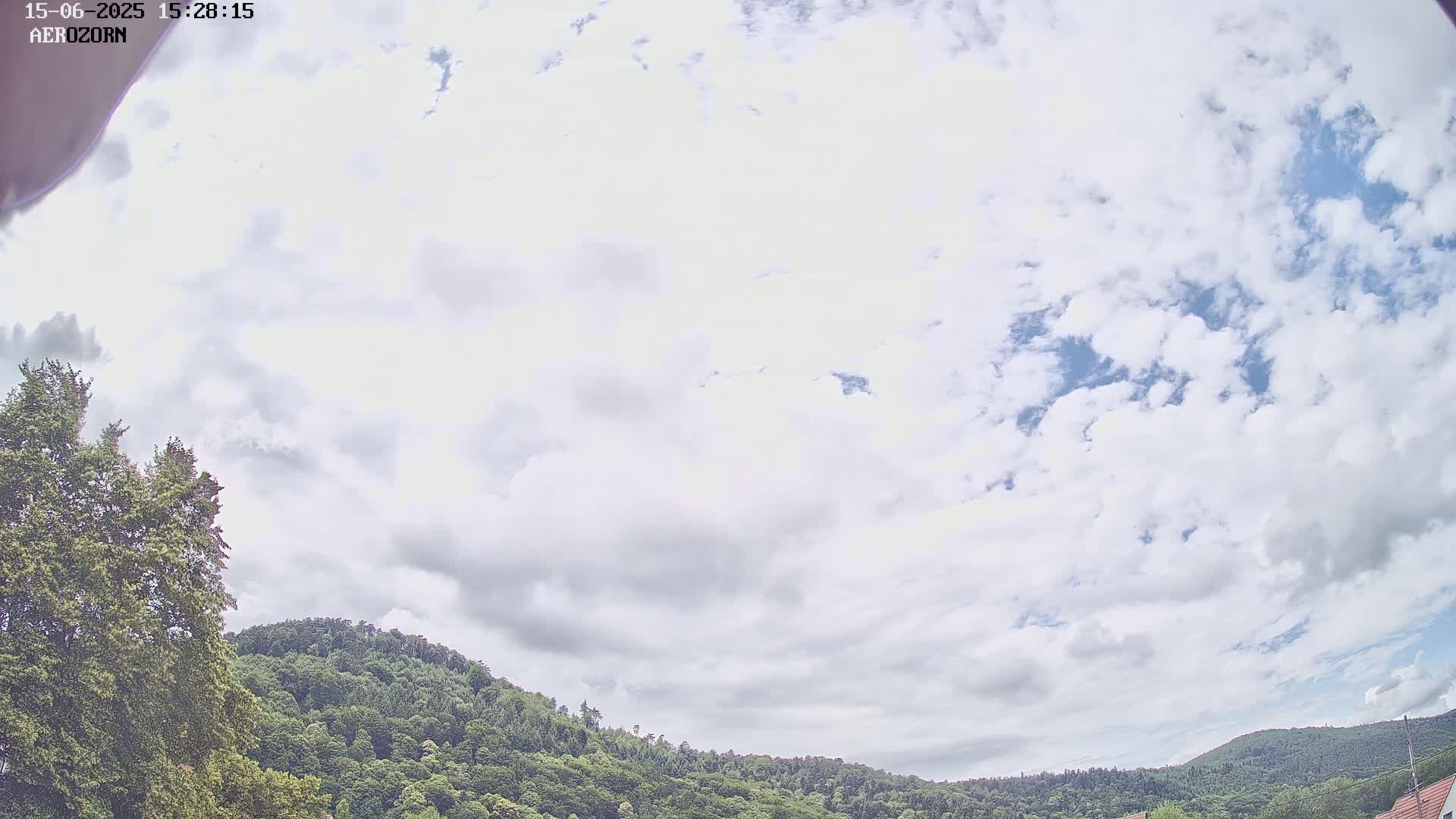 A partly cloudy sky is visible above a line of green, tree-covered hills.