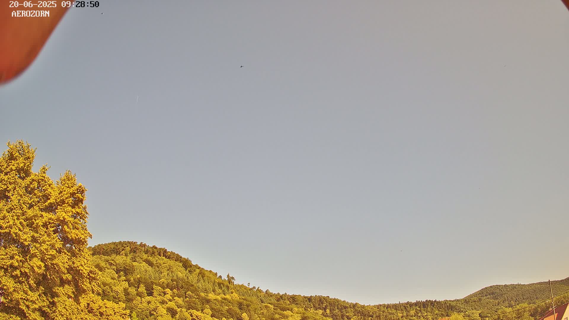A mostly clear sky is visible above a lush green and yellow hillside.