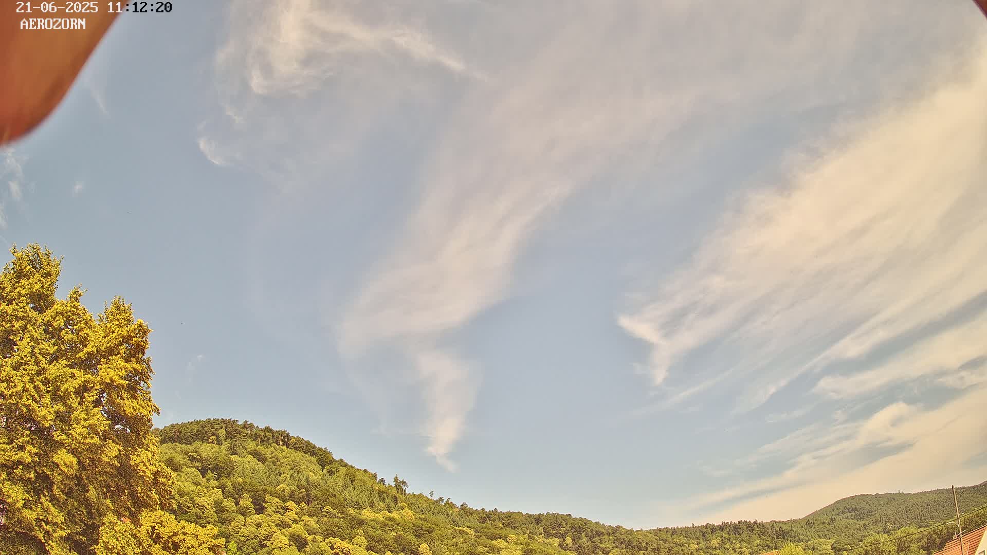 A partly cloudy sky above a lush green hillside.