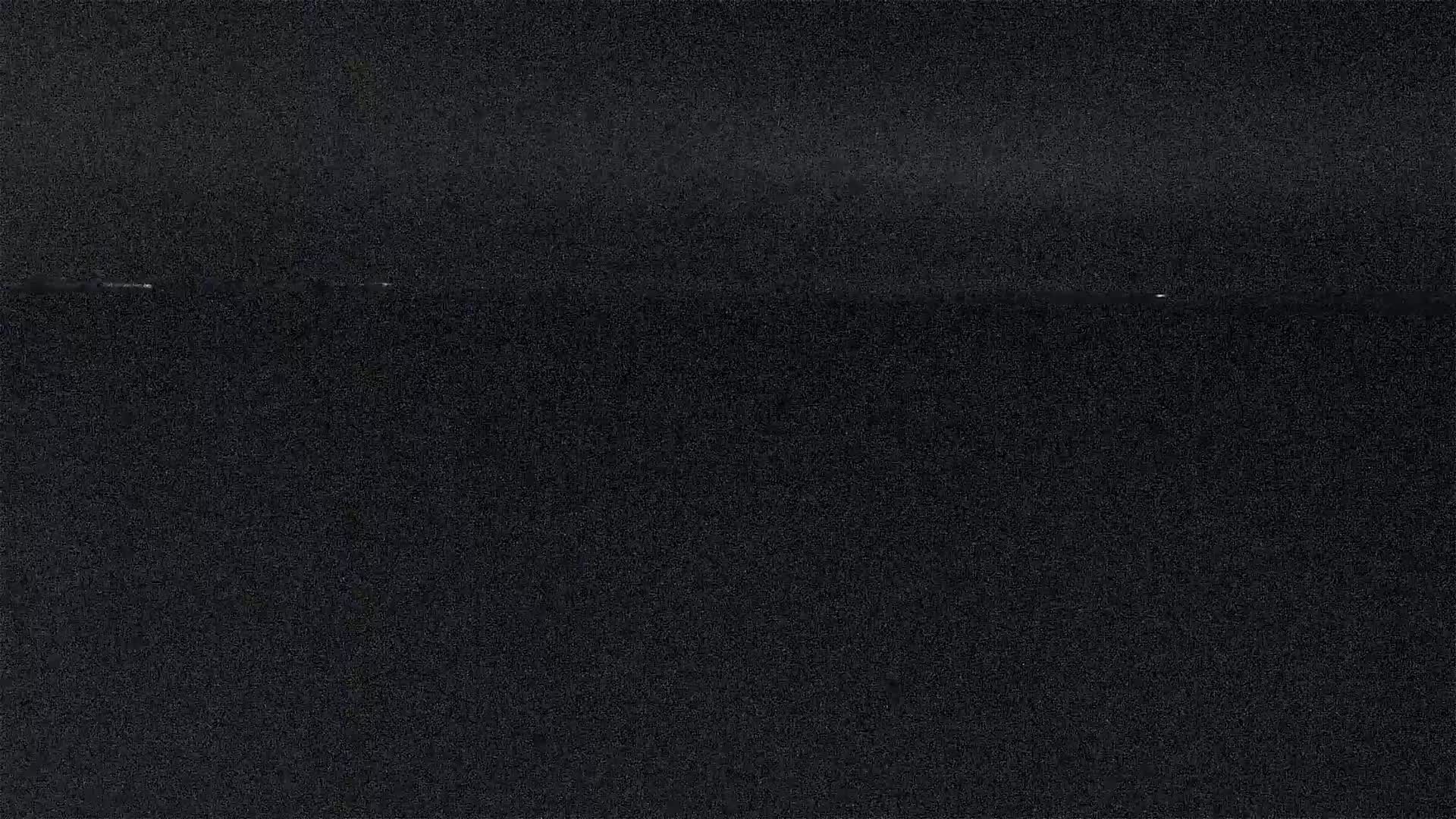 A dark, grainy image shows a dimly lit horizon line, possibly at night.