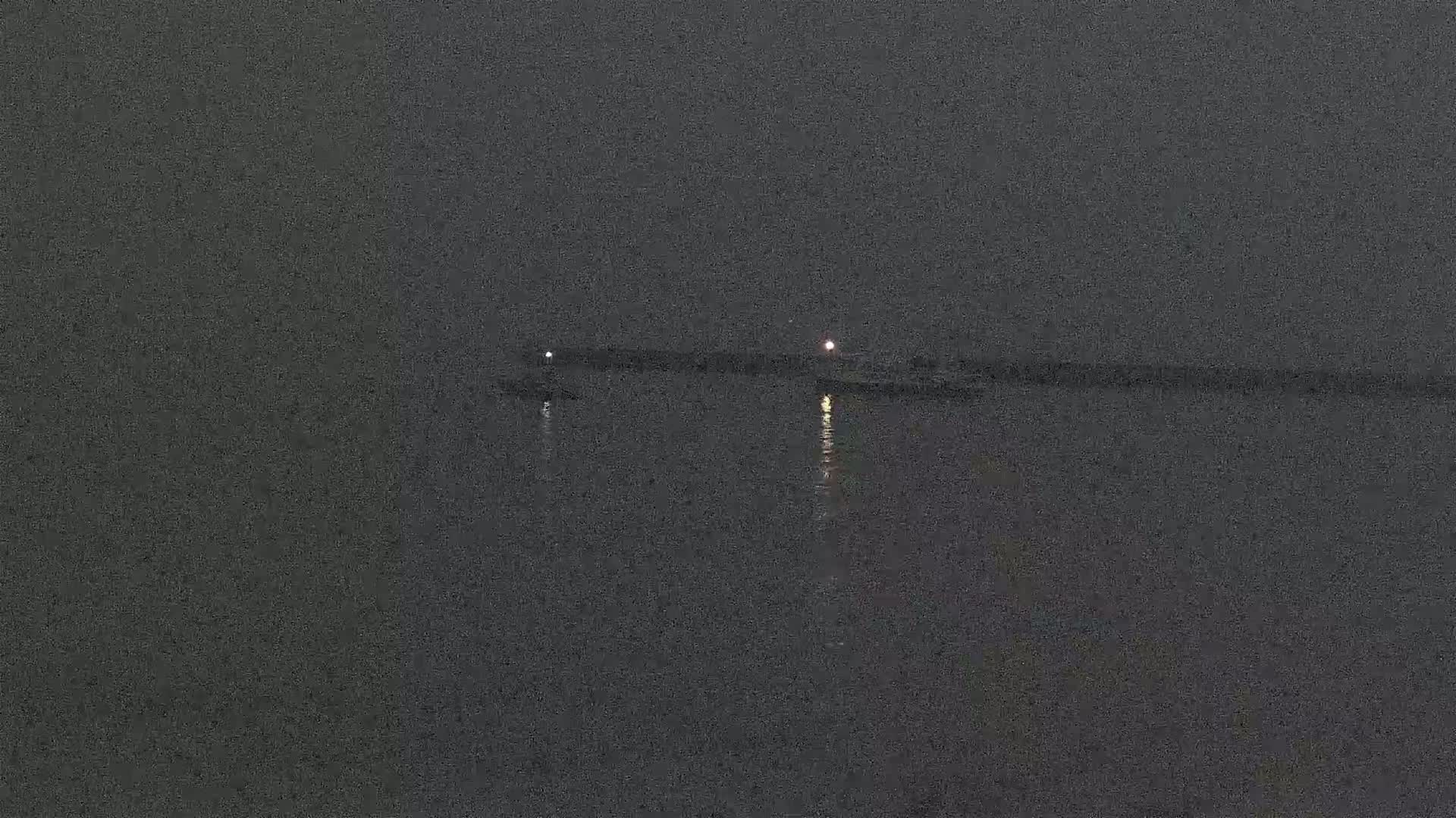 Two small lights are visible on a dark body of water at night.