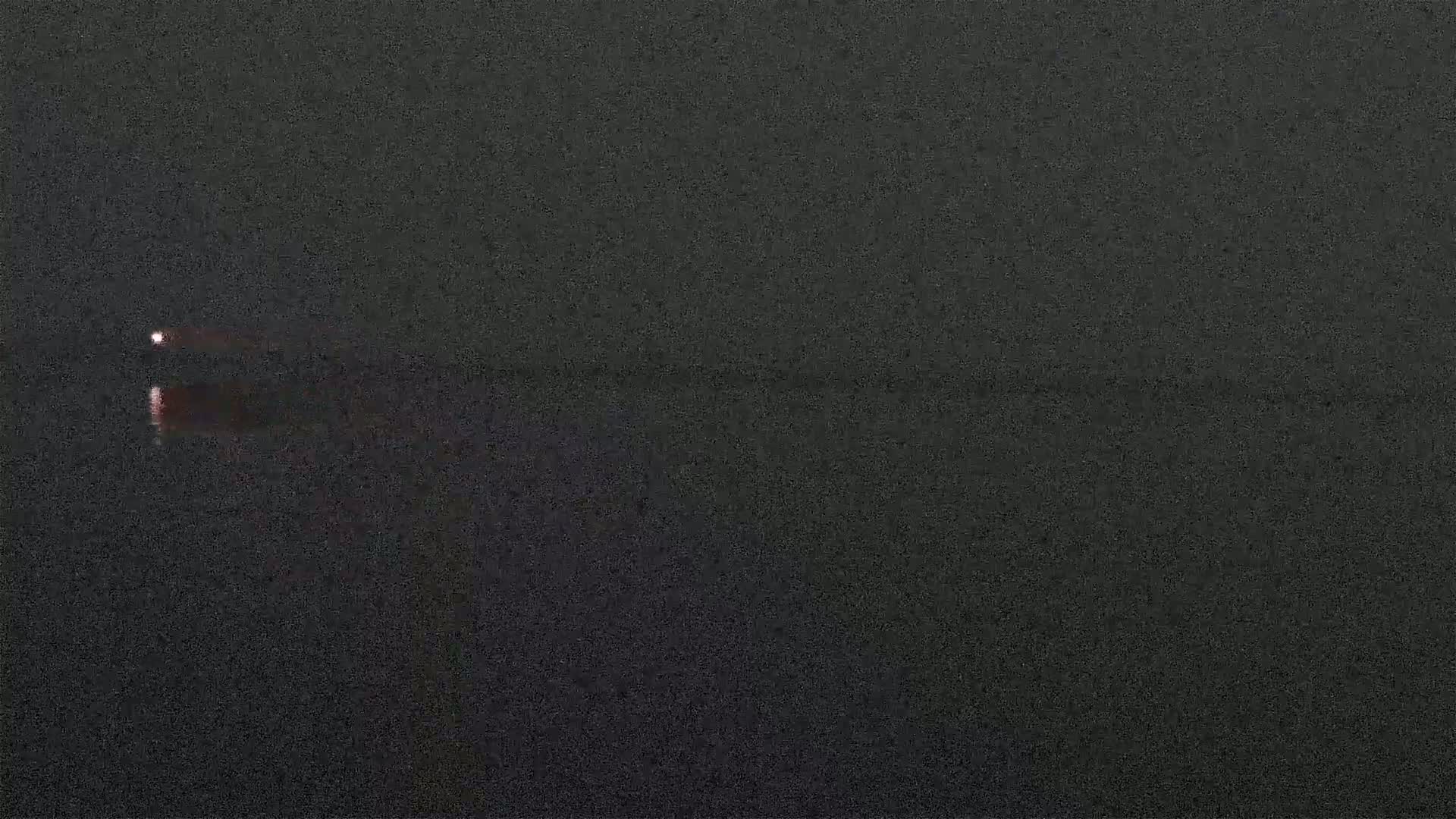 Two faint lights are visible on a dark, still body of water under a dark sky.
