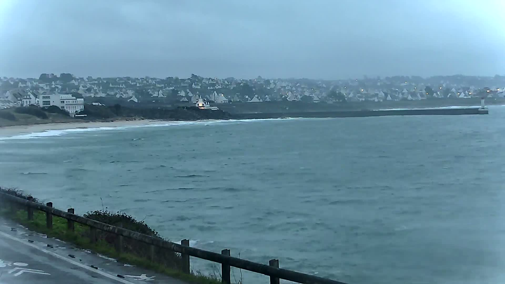 A coastal town is visible across a choppy sea under an overcast sky.