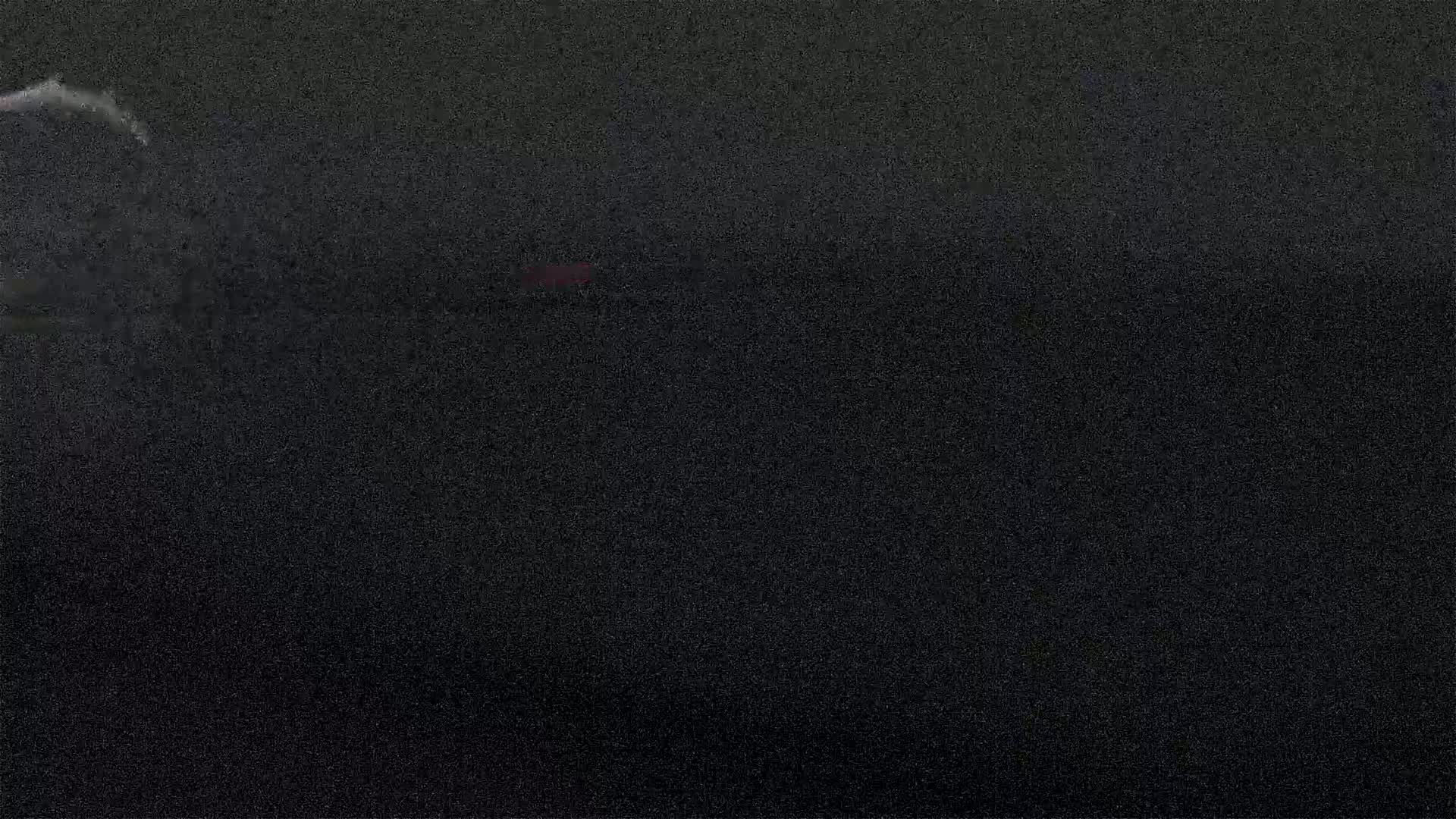 A dark, grainy image shows a hint of red in the middle distance.