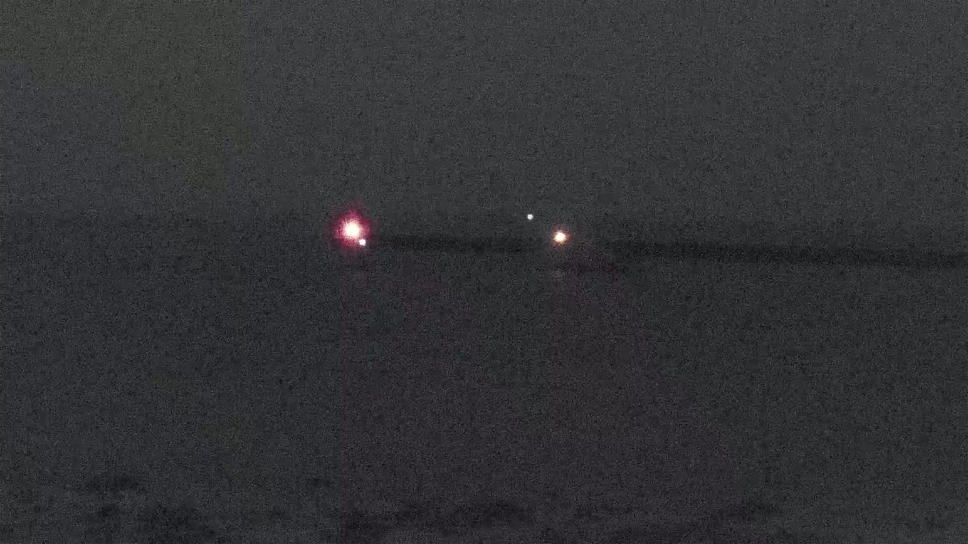 Three faint lights are visible on a dark, nighttime horizon.