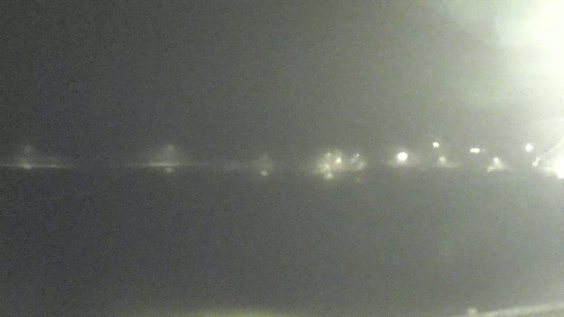 A blurry, nighttime image shows distant lights in hazy or foggy conditions.