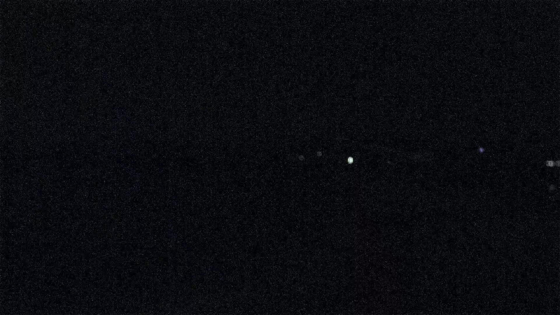 A dark, nighttime scene shows several faint lights in the distance.