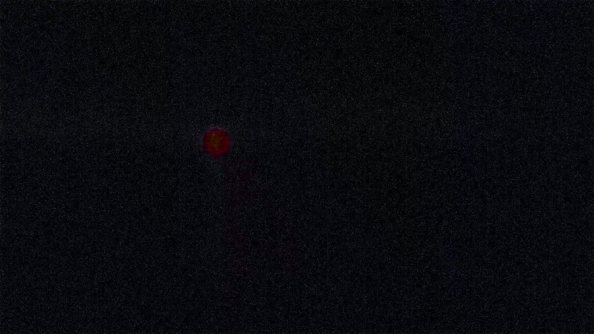 A blurry, red-orange light appears in a dark, speckled background.